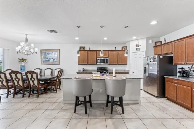 a kitchen with a dining table chairs stainless steel appliances and cabinets