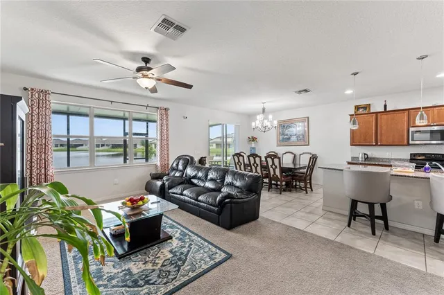 a living room with furniture kitchen view and a large window