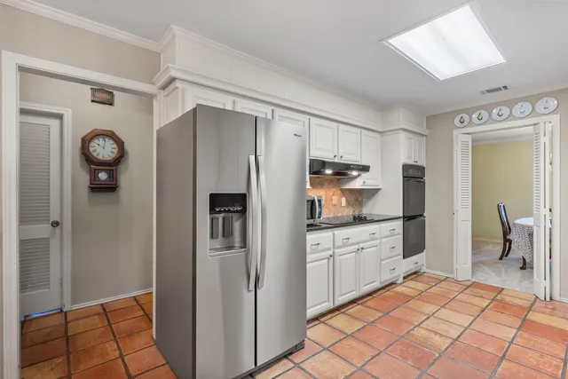 a kitchen with granite countertop a refrigerator and a stove top oven
