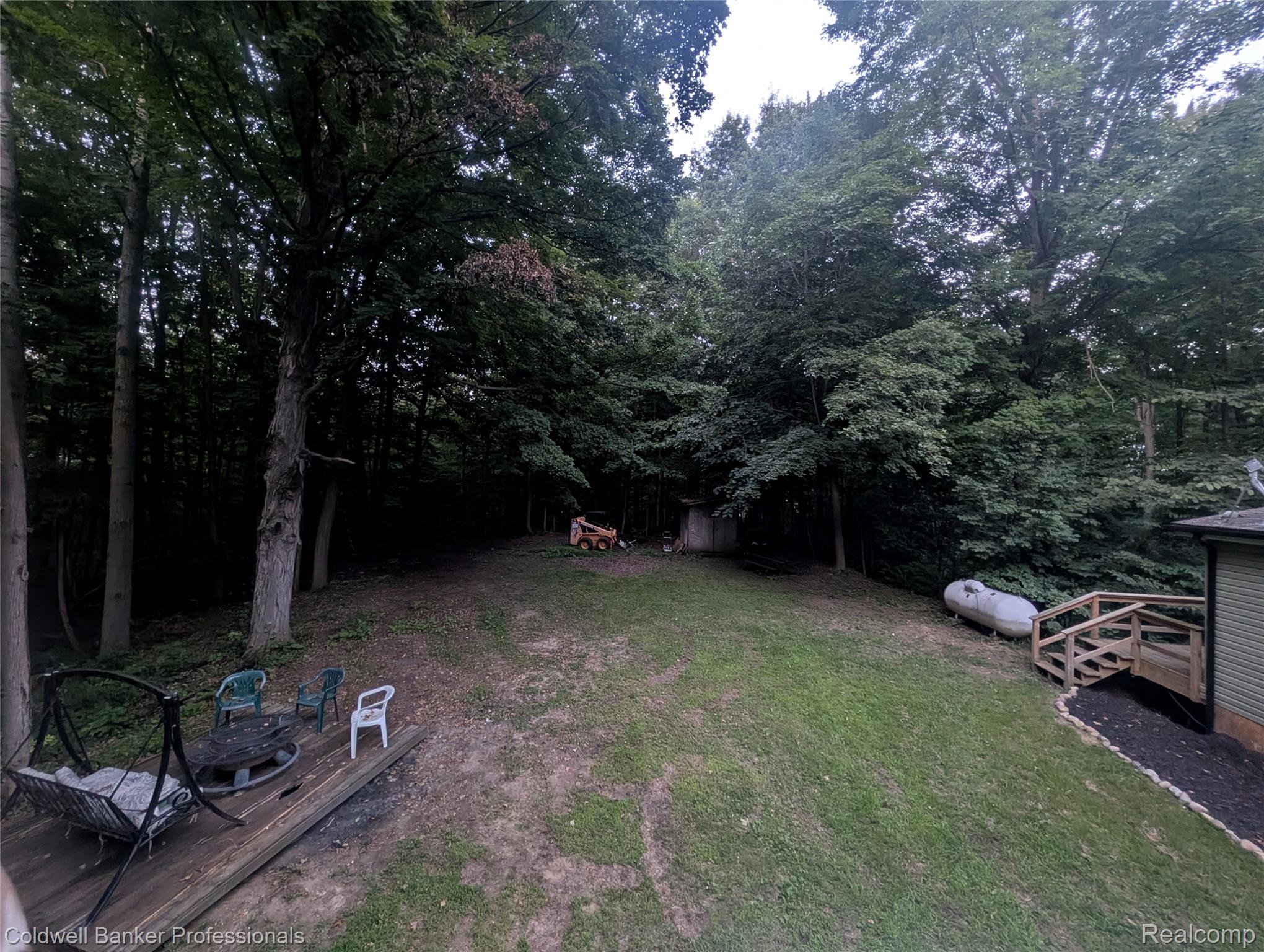 5323 English Road Clifford, MI 48727 - Photo 6 of 46 Expansive yard featuring mature trees, a natural gas tank, and a wooden deck with a fire pit