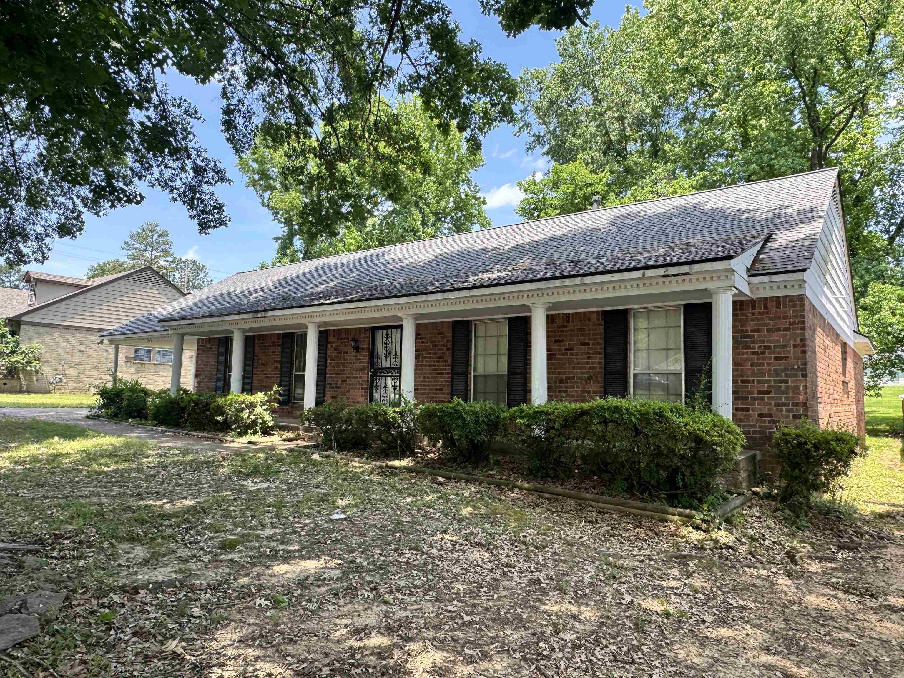 5520 Wagon Rd Gap, Unit GAP Memphis, TN 38134 - Photo 2 of 19 Brick ranch-style residence featuring a covered porch with white columns, black window shutters, and mature front landscaping