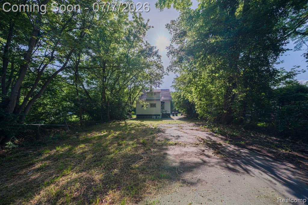 18486 Trinity Street Detroit, MI 48219 - Photo 18 of 19 Gravel driveway leading to a residence with light-colored siding and a gabled roof