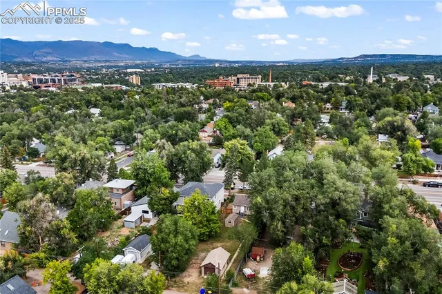 an aerial view of a residential houses with outdoor space and trees all around