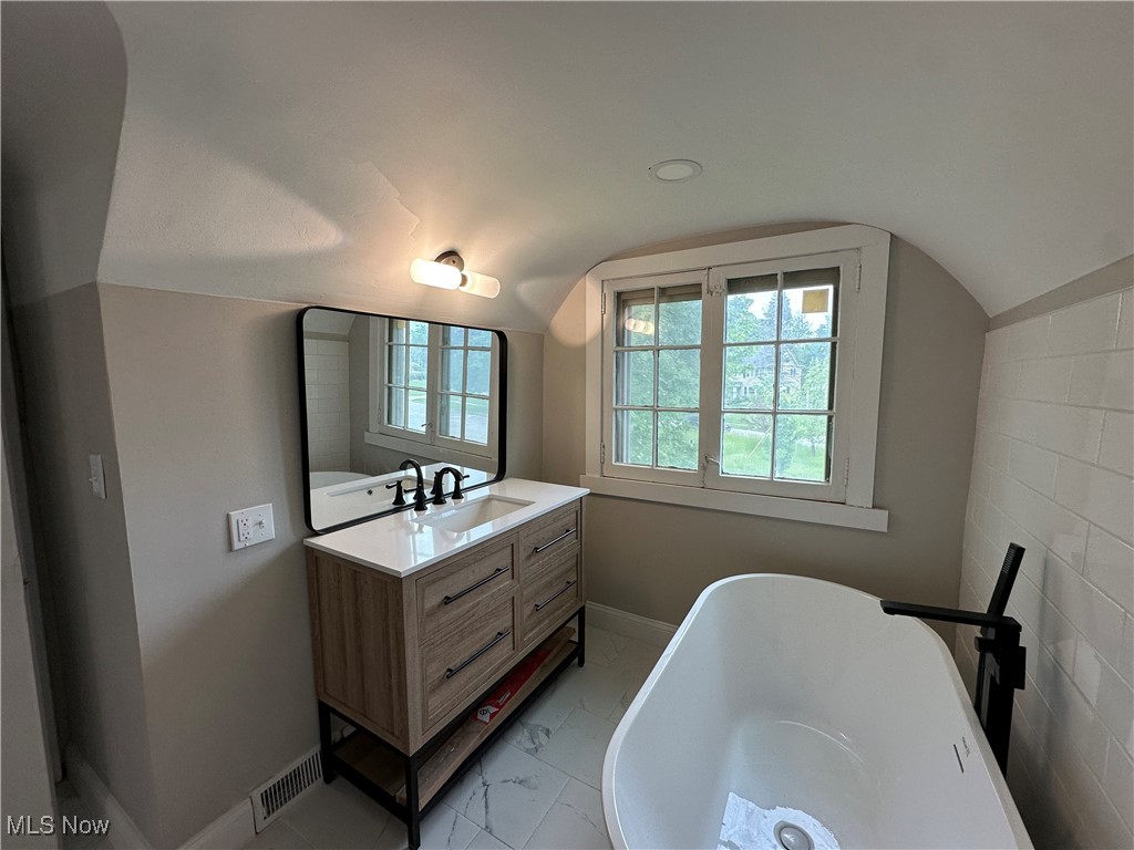 13707 Drexmore Road Cleveland, OH 44120 - Photo 20 of 35 Primary Bathroom vanity, baseboards, marble look tiles, and lofted ceiling
