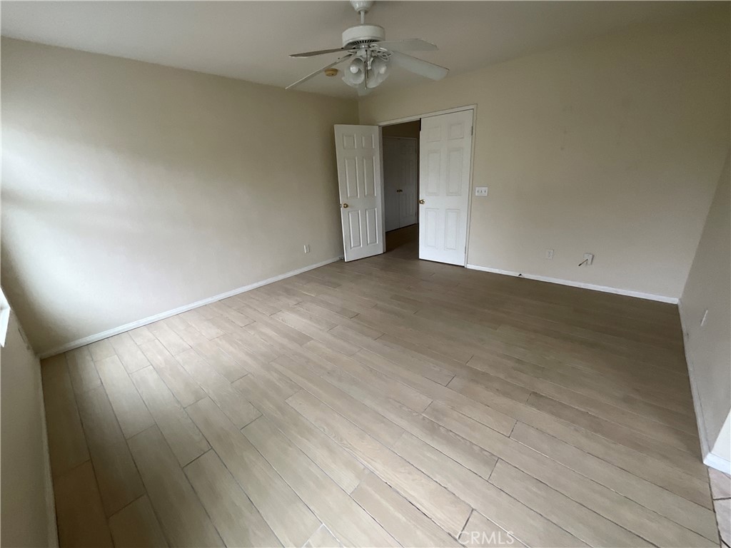 11875 Cedarbrook Place Rancho Cucamonga, CA 91730 - Photo 15 of 26 an empty room with wooden floor chandelier fan and windows