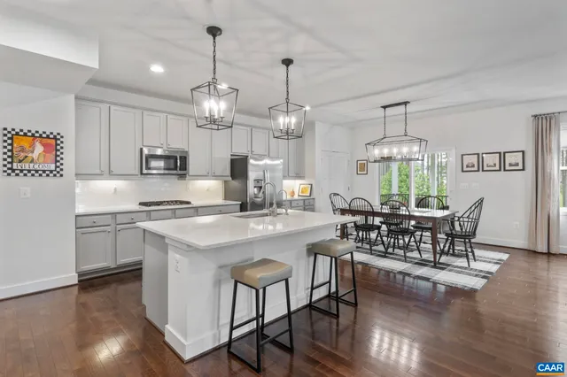 a kitchen with stainless steel appliances a dining table chairs stove and white cabinets