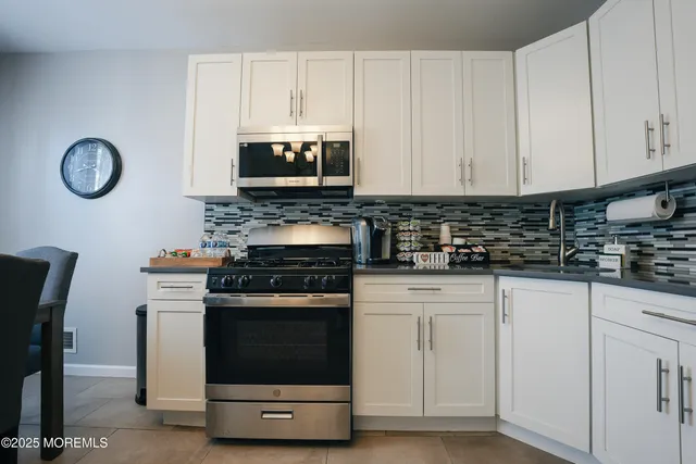 a kitchen with white cabinets and appliances