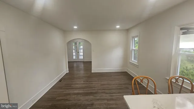 a view of a hallway to a house with wooden floor and windows