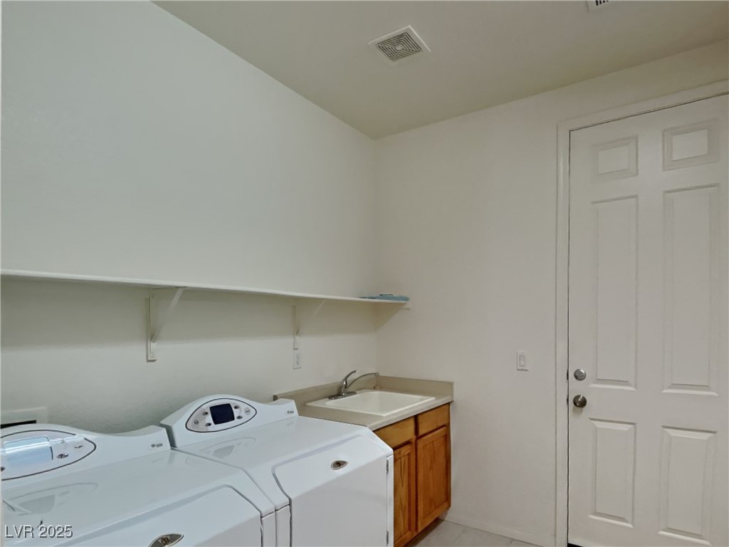 9456 Bluff Ledge Avenue Las Vegas, NV 89149 - Photo 18 of 35 Laundry area with washer and clothes dryer, light tile patterned flooring, and cabinet space