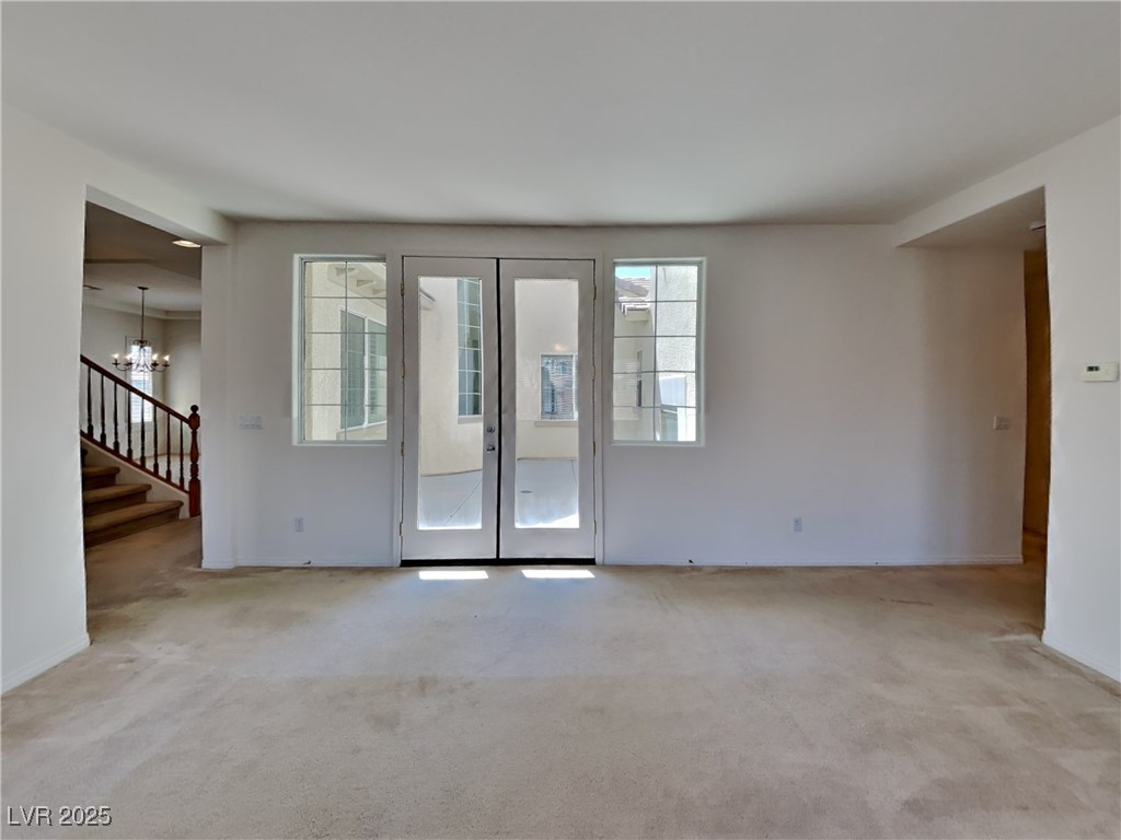 9456 Bluff Ledge Avenue Las Vegas, NV 89149 - Photo 27 of 35 Unfurnished room featuring french doors, light carpet, a chandelier, and stairs