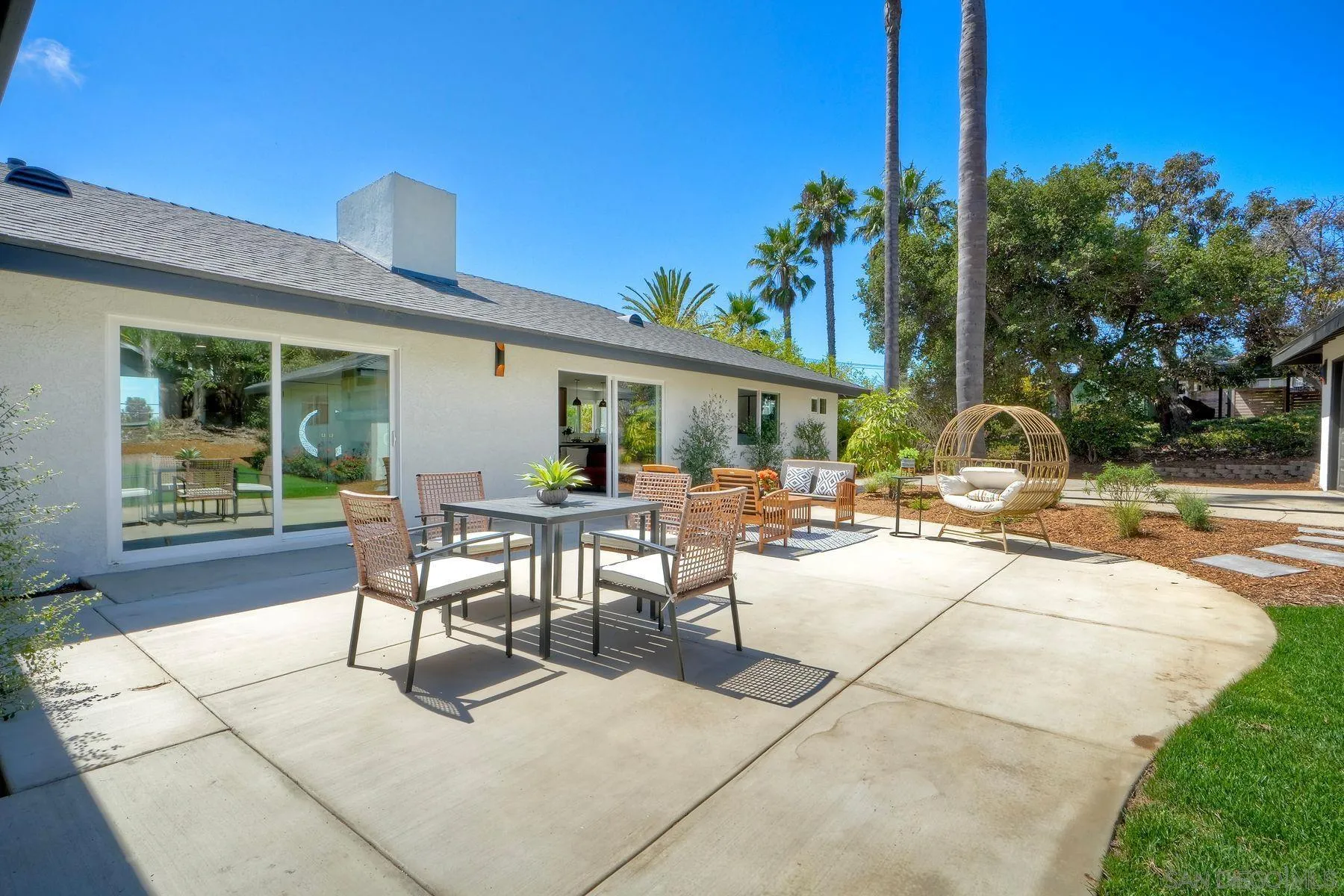 1870 Laurel Road Oceanside, CA 92054 - Photo 41 of 57 a view of a patio with dining table and chairs with plants and palm trees
