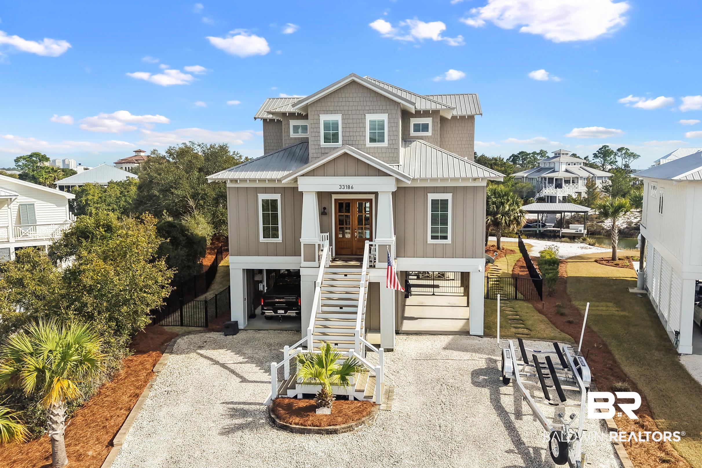 33186 Marlin Key Drive Orange Beach, AL 36561 - Photo 9 of 87 Raised beach house featuring driveway, board and batten siding, a garage, french doors, and a metal roof