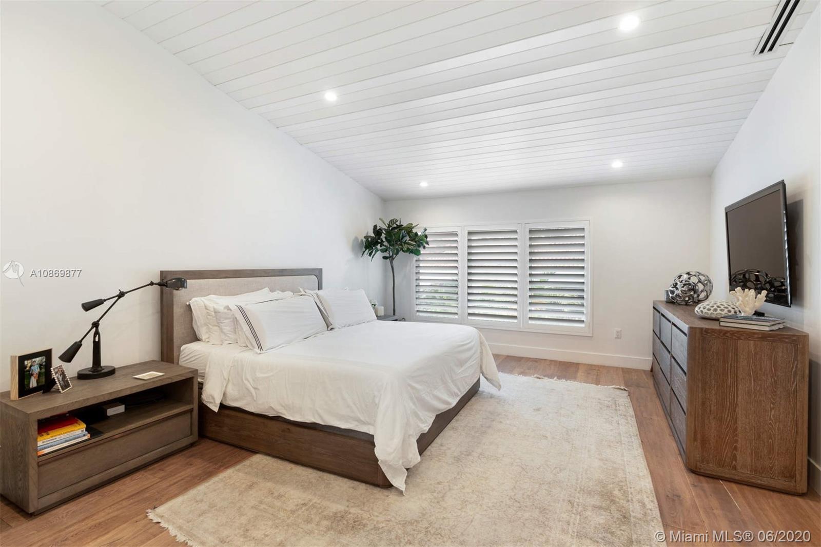 677 Ridgewood Road Key Biscayne, FL 33149 - Photo 25 of 38 a spacious bedroom with a bed and a flat screen tv