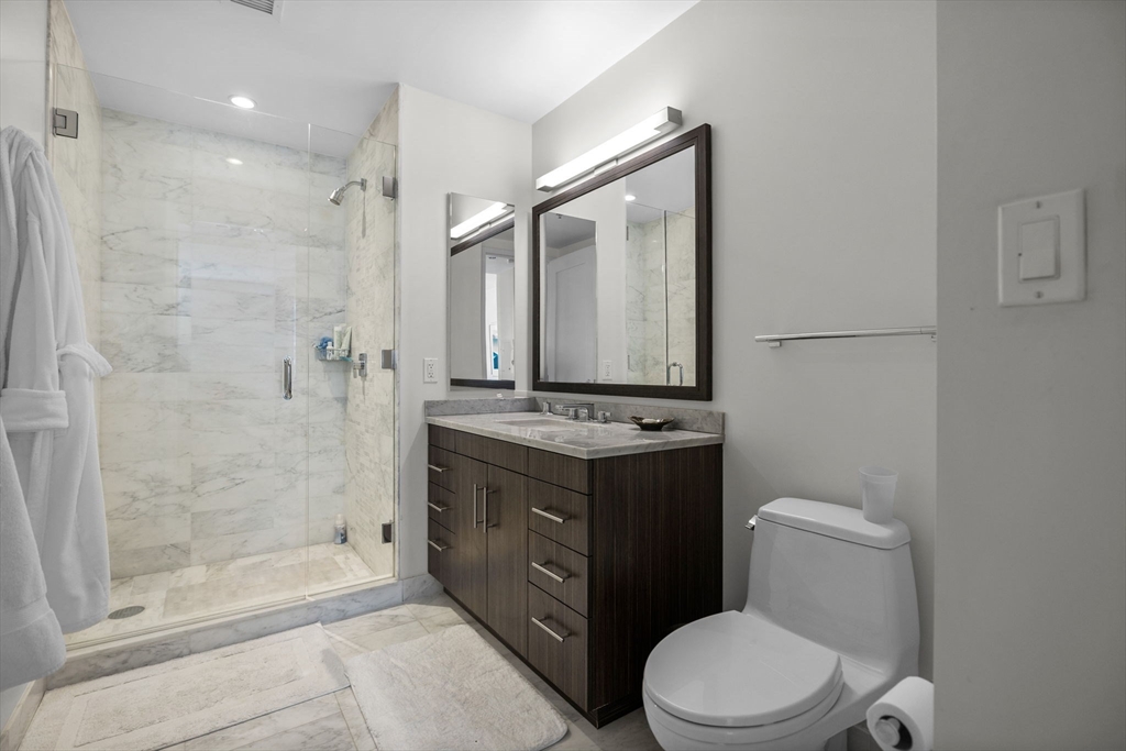 580 Washington Street, Unit 411 Boston, MA 02111 - Photo 13 of 24 a bathroom with a granite countertop toilet sink and shower