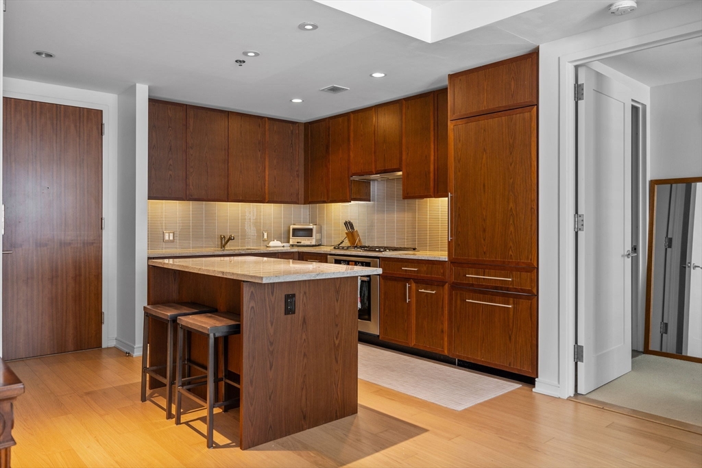 580 Washington Street, Unit 411 Boston, MA 02111 - Photo 7 of 24 a kitchen with granite countertop a refrigerator and a stove top oven