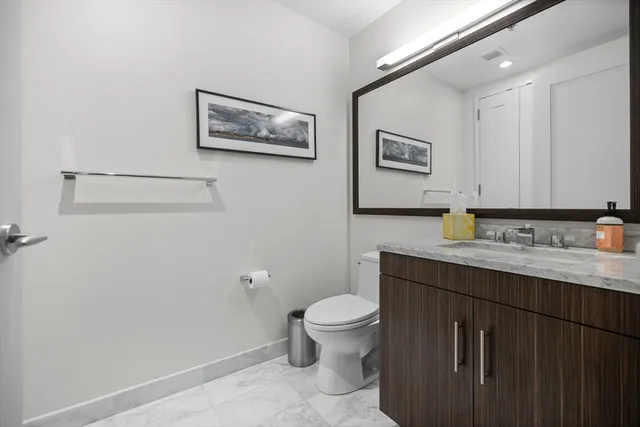 a bathroom with a granite countertop toilet a sink and mirror