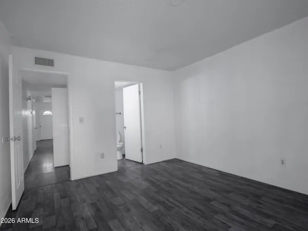 a view of an empty room with wooden floor and a bathroom