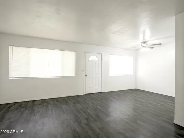 an empty room with wooden floor and windows