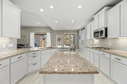 a large kitchen with kitchen island granite countertop a large counter top space appliances and cabinets