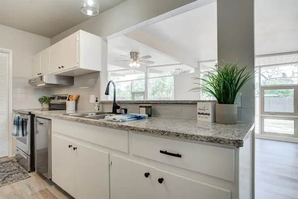 a kitchen with stainless steel appliances granite countertop a sink a stove and a window