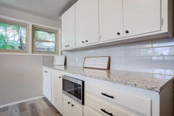 a kitchen with granite countertop white cabinets and white appliances