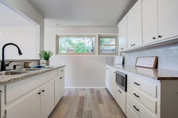 a kitchen with granite countertop white cabinets and white appliances