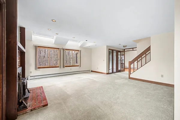 a view of an empty room with fireplace and stairs