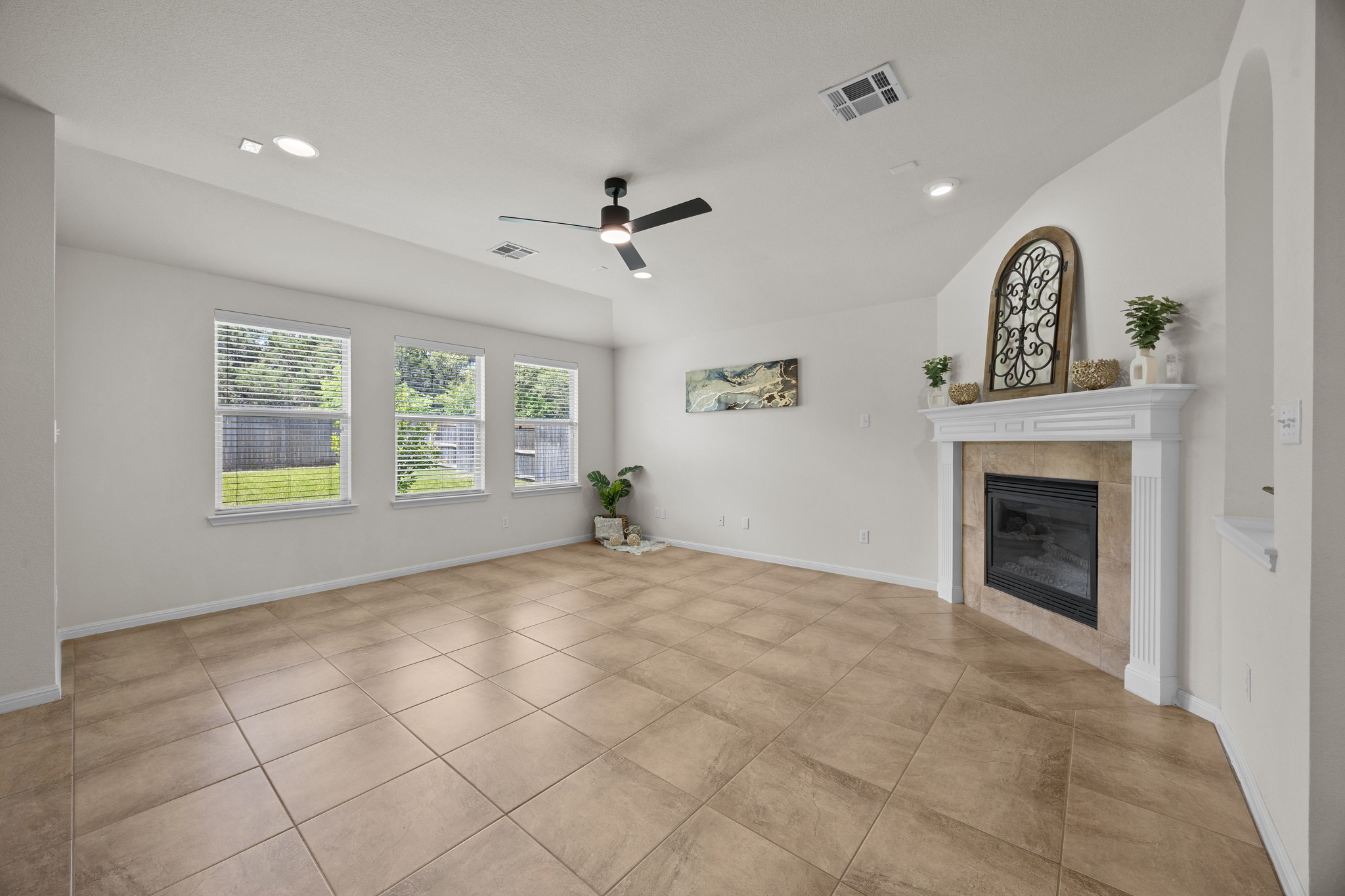 1317 Rimstone Drive Cedar Park, TX 78613 - Photo 12 of 32 Unfurnished living room featuring a ceiling fan, a fireplace, recessed lighting, lofted ceiling, and light tile patterned floors