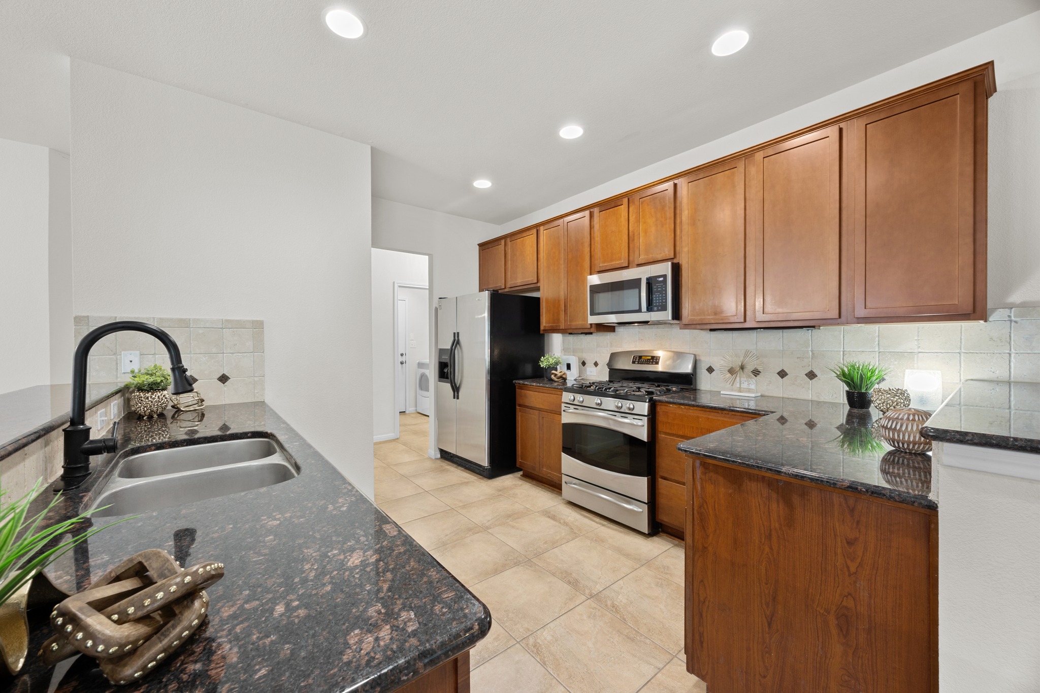 1317 Rimstone Drive Cedar Park, TX 78613 - Photo 16 of 32 Kitchen with dark stone counters, stainless steel appliances, wood finish cabinetry, a peninsula, and recessed lighting