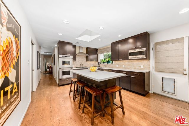 a kitchen with stainless steel appliances kitchen island granite countertop a table chairs and a refrigerator