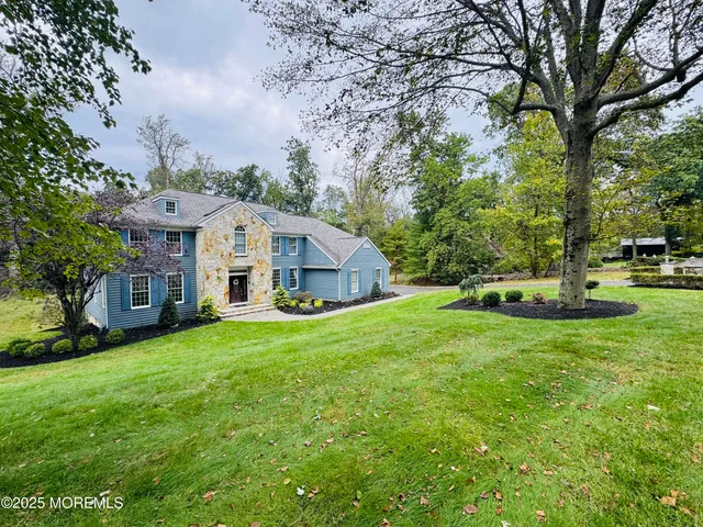a view of a house with a big yard plants and large trees