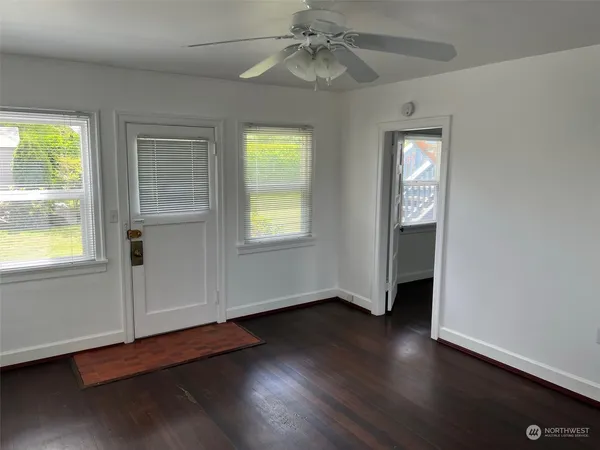 an empty room with wooden floor closet and windows