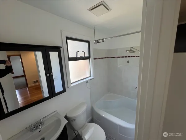 a bathroom with a tub toilet a sink and mirror