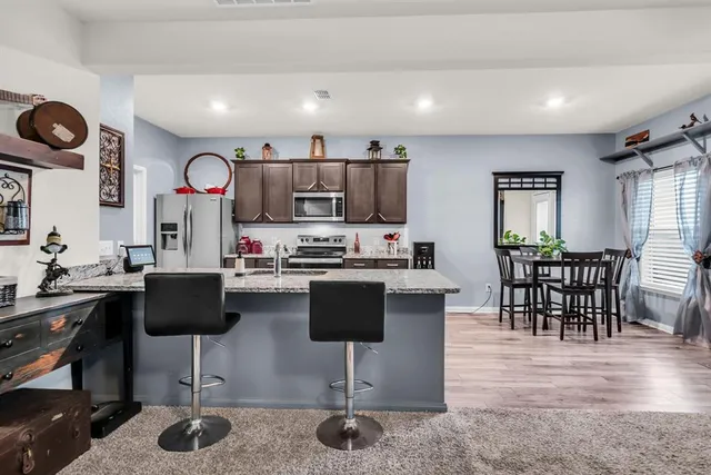 a kitchen with stainless steel appliances granite countertop a stove a refrigerator a kitchen island with a dining table and chairs