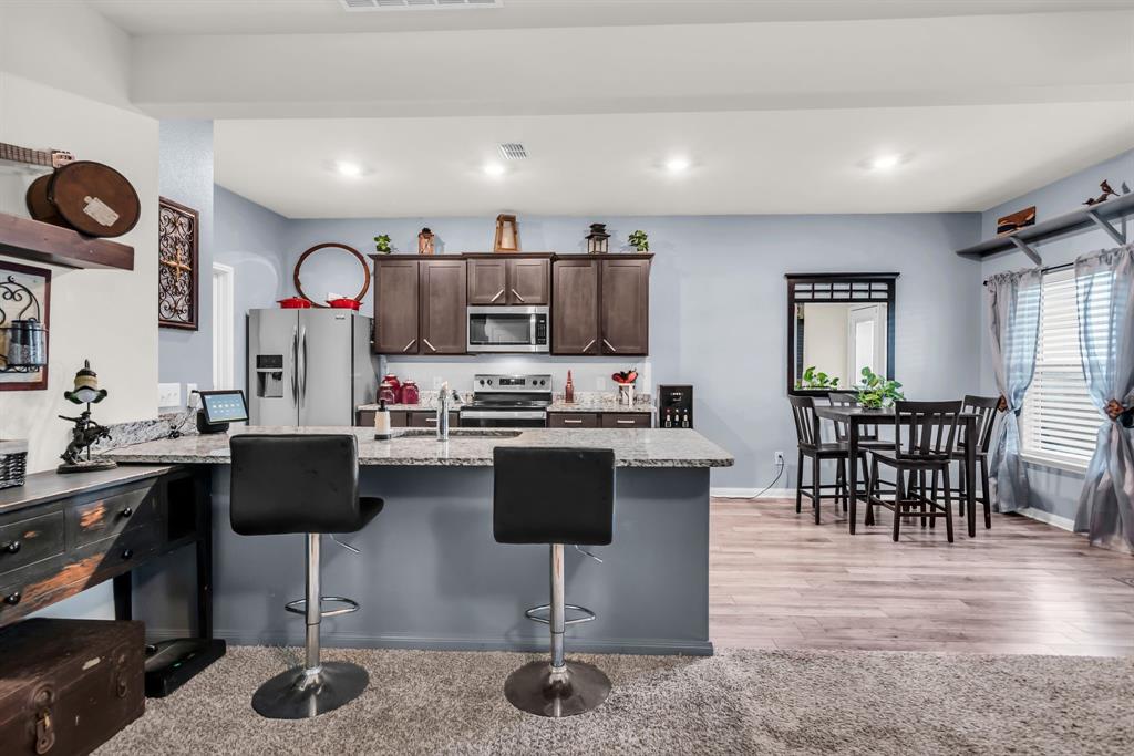 189 Point Rider Road Newark, TX 76071 - Photo 11 of 40 a kitchen with stainless steel appliances granite countertop a stove a refrigerator a kitchen island with a dining table and chairs