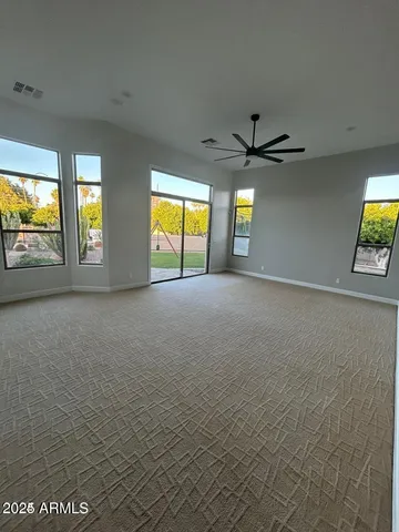 an empty room with windows and ceiling fan