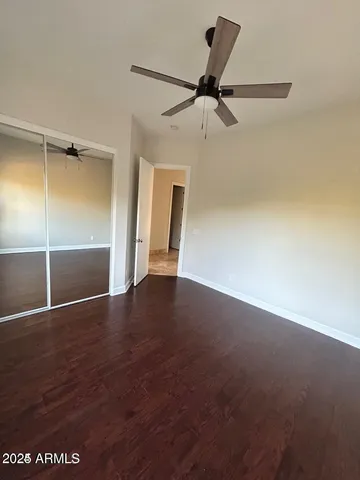 an empty room with wooden floor and fan