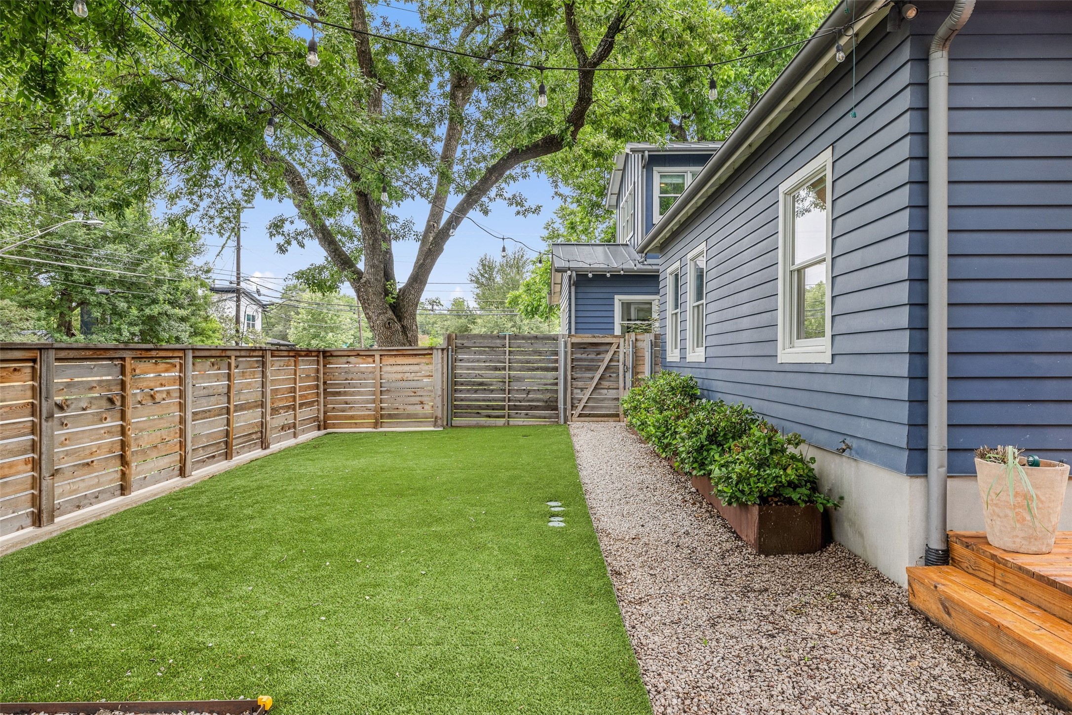 2000 Rundell Place Austin, TX 78704 - Photo 36 of 38 A well-maintained side yard features a gravel path, verdant landscaping, and a secure privacy fence.