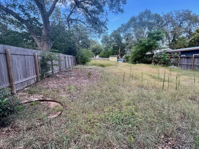 a view of backyard with table and chairs and wooden fence