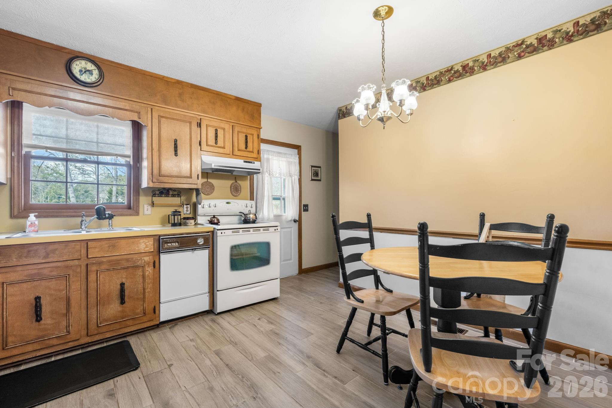 3384 Sheely Road Lenoir, NC 28645 - Photo 15 of 27 a kitchen with stainless steel appliances granite countertop a stove a sink dishwasher a dining table and chair with wooden floor