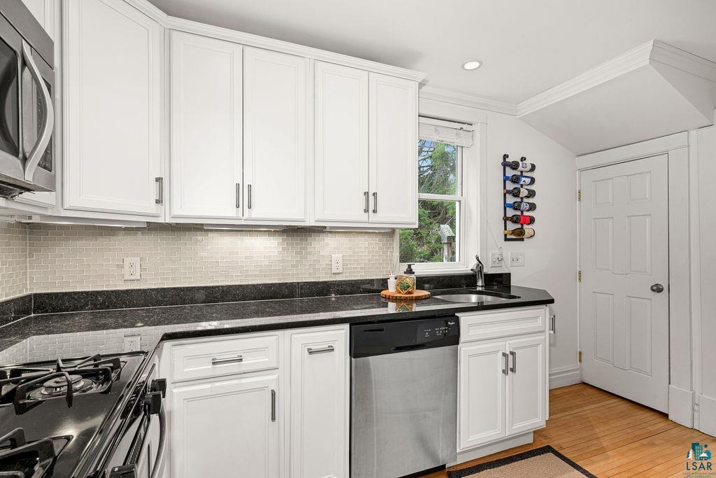 3206 Minnesota Avenue Duluth, MN 55802 - Photo 13 of 51 Kitchen featuring white cabinetry, dark granite countertops, a tile backsplash, mood accent lighting, stainless steel dishwasher, and a gas stove