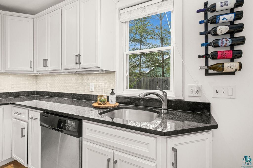 3206 Minnesota Avenue Duluth, MN 55802 - Photo 14 of 51 Contemporary kitchen featuring white cabinetry with dark hardware, a stainless steel dishwasher, a single basin sink with a gooseneck faucet, black granite countertops, and a light-toned tile backsplash
