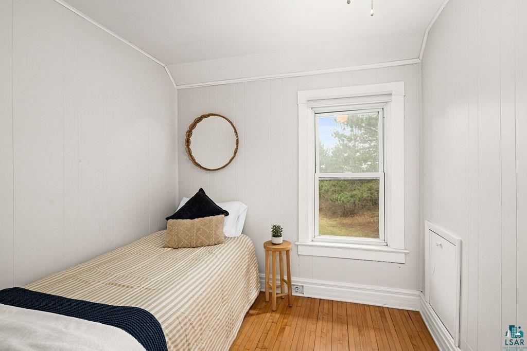3206 Minnesota Avenue Duluth, MN 55802 - Photo 21 of 51 Hardwood flooring with a natural finish, vertical paneling on walls, a double-hung window with white trim, and a built-in access panel