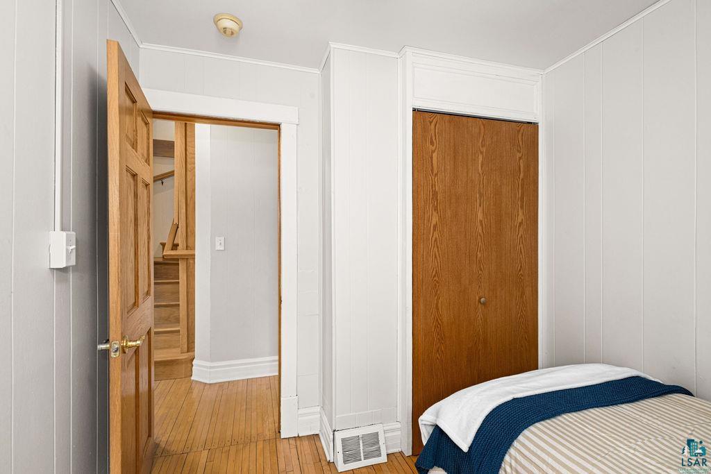 3206 Minnesota Avenue Duluth, MN 55802 - Photo 22 of 51 Interior room featuring light-colored vertical paneling, hardwood flooring, and a natural wood-finish door