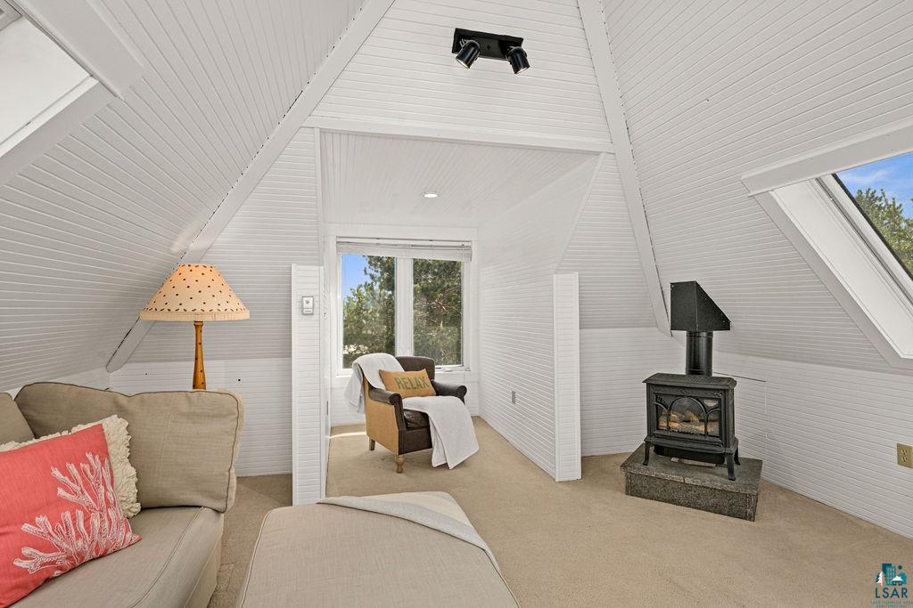 3206 Minnesota Avenue Duluth, MN 55802 - Photo 27 of 51 Flexible Space featuring white beadboard walls and ceilings, a cast iron stove on a stone base, and a large fixed window facing Lake Superior