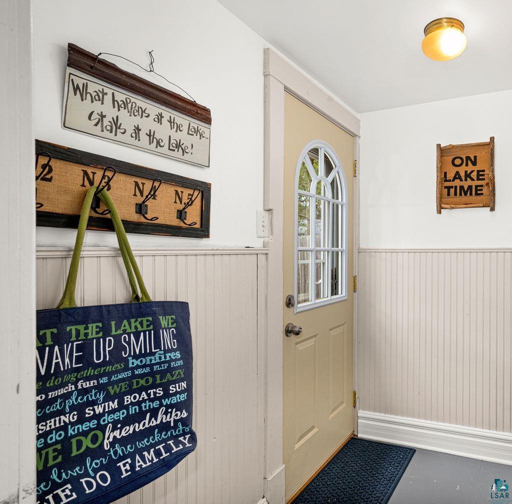 3206 Minnesota Avenue Duluth, MN 55802 - Photo 31 of 51 Backdoor Entryway & Mudroom featuring a paneled door with an arched window, beadboard wainscoting, a flush-mount ceiling light, and dark-toned flooring leading to the backyard