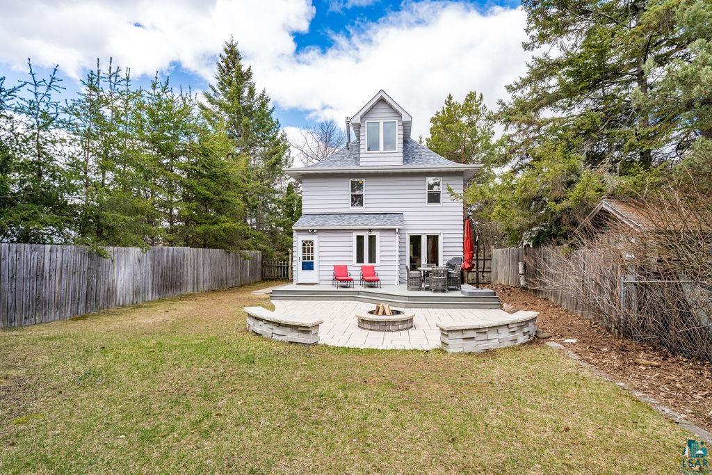 3206 Minnesota Avenue Duluth, MN 55802 - Photo 32 of 51 Expansive backyard featuring a large stone patio, built-in fire pit, stone retaining walls, and a wooden privacy fence