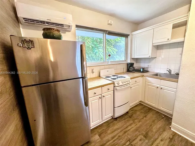 a kitchen with a stove a sink and white cabinets with wooden floor