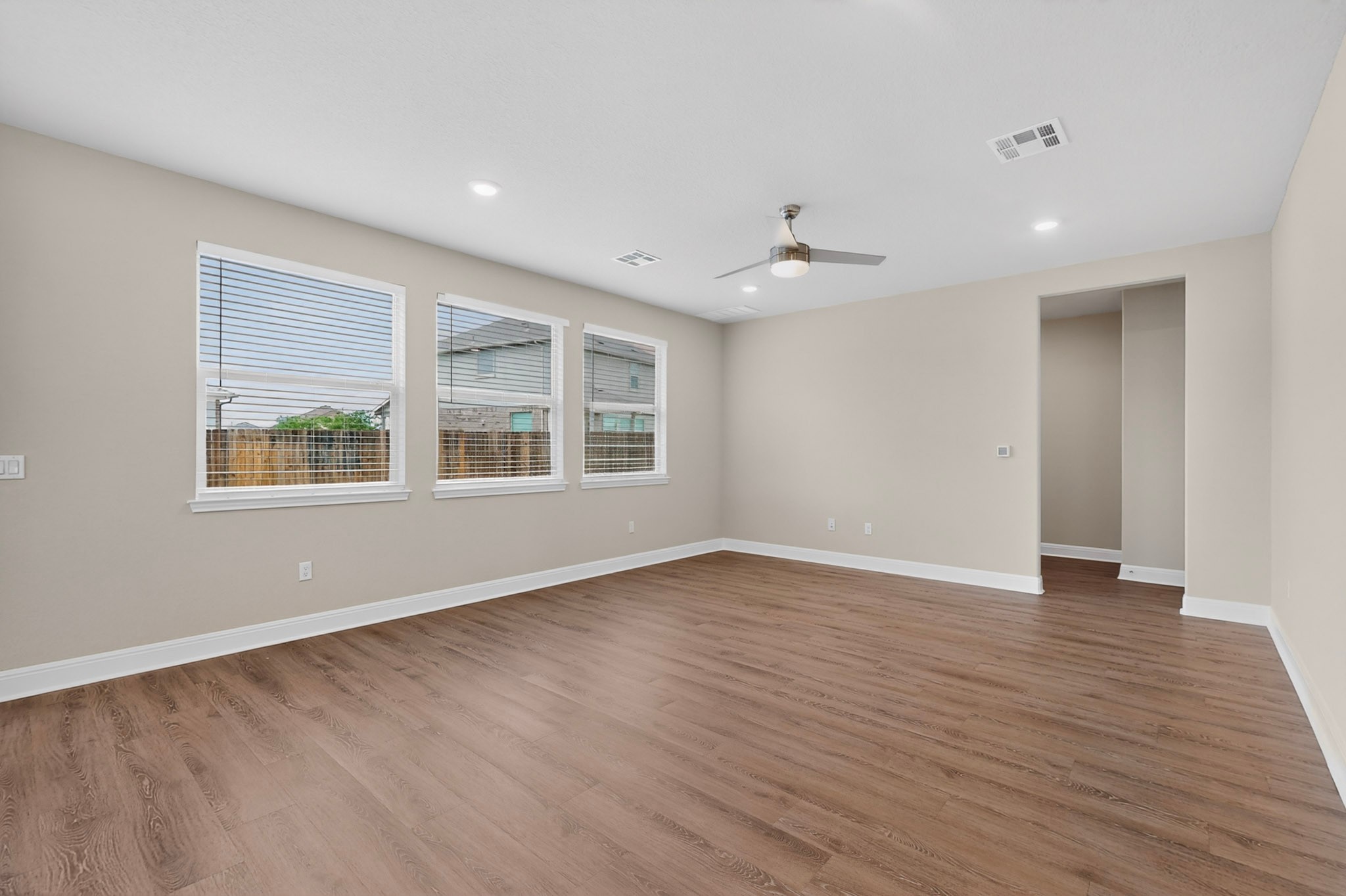 16809 Guido Cove Pflugerville, TX 78660 - Photo 5 of 40 Spacious living area featuring wood-finish flooring, neutral wall tones, and three large windows with blinds
