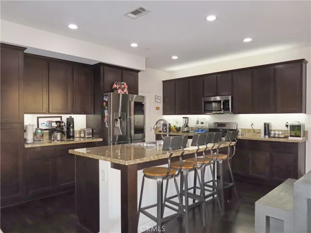 a kitchen with kitchen island granite countertop wooden cabinets and refrigerator